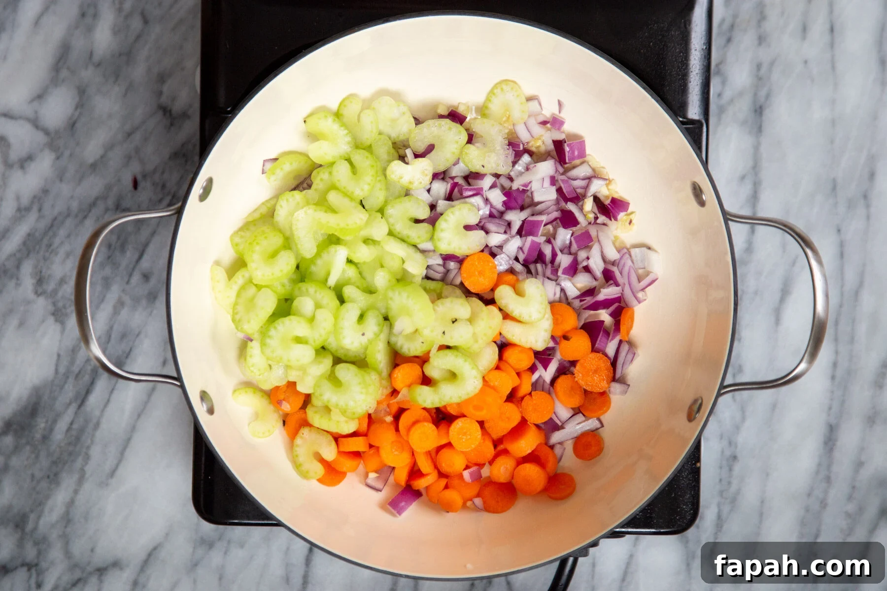 celery, carrots and onions in a sauteeing pan 