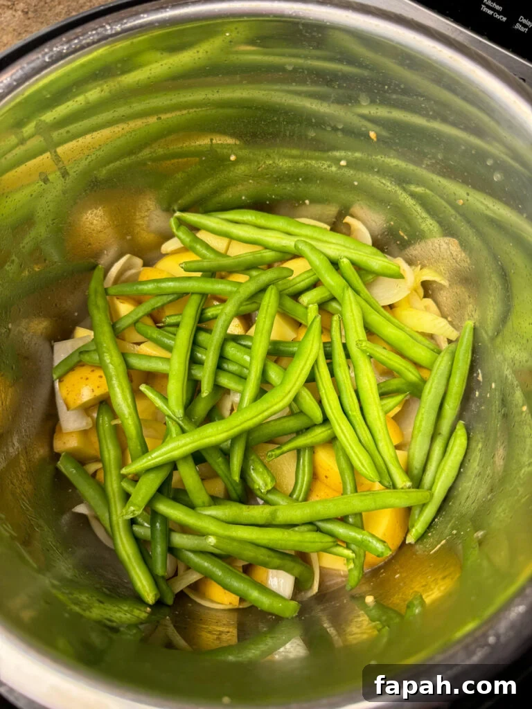 A layer of fresh green beans added to potatoes in an Instant Pot.