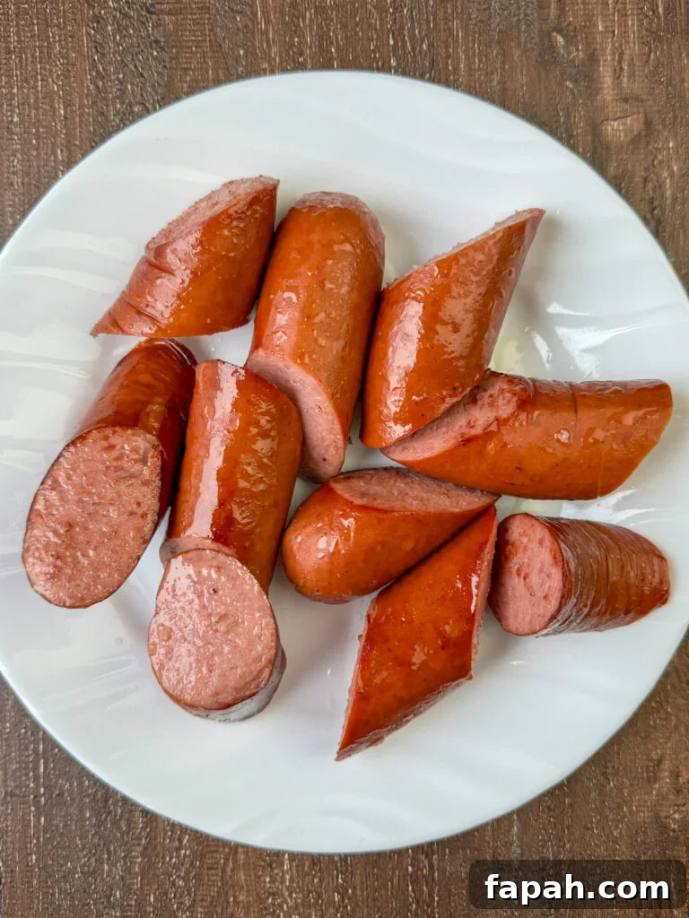 Chunks of browned sausage set aside on a plate on a wooden counter top.