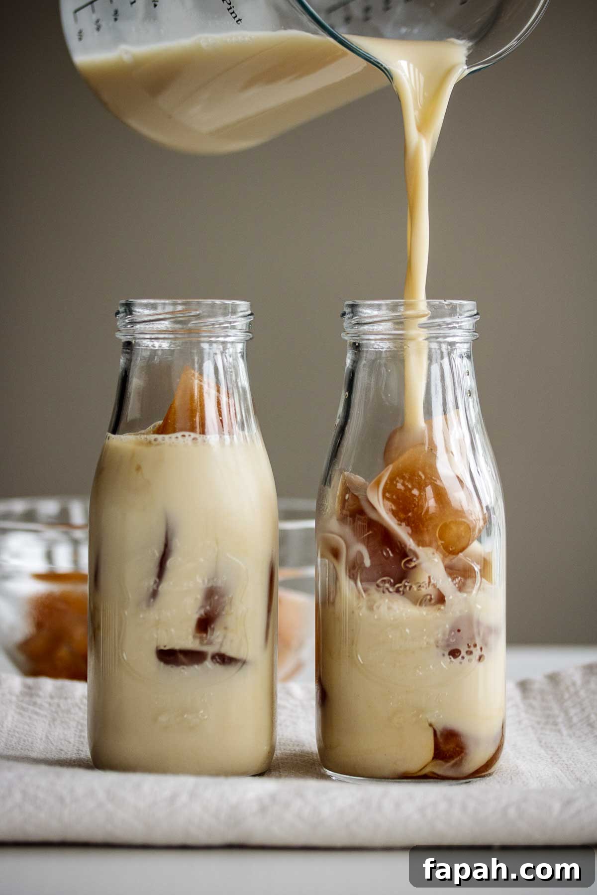 Cold brew milk tea pouring over ice cubes.