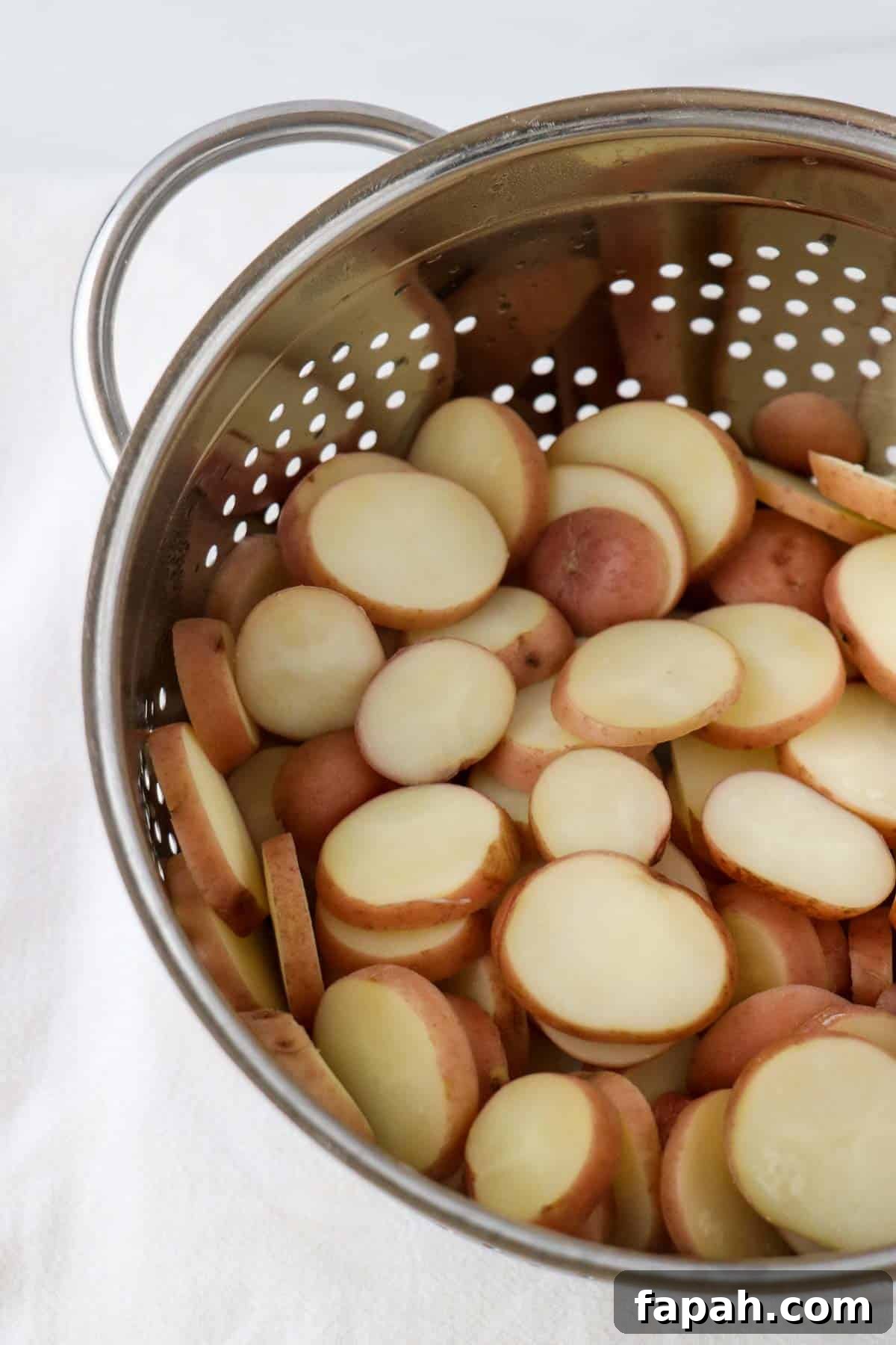 Sliced baby red potatoes in a metal colander.