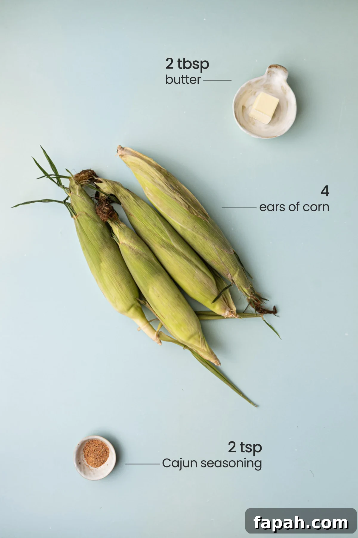 All the ingredients for Cajun corn on the cob - butter, ears of corn, and Cajun seasoning.