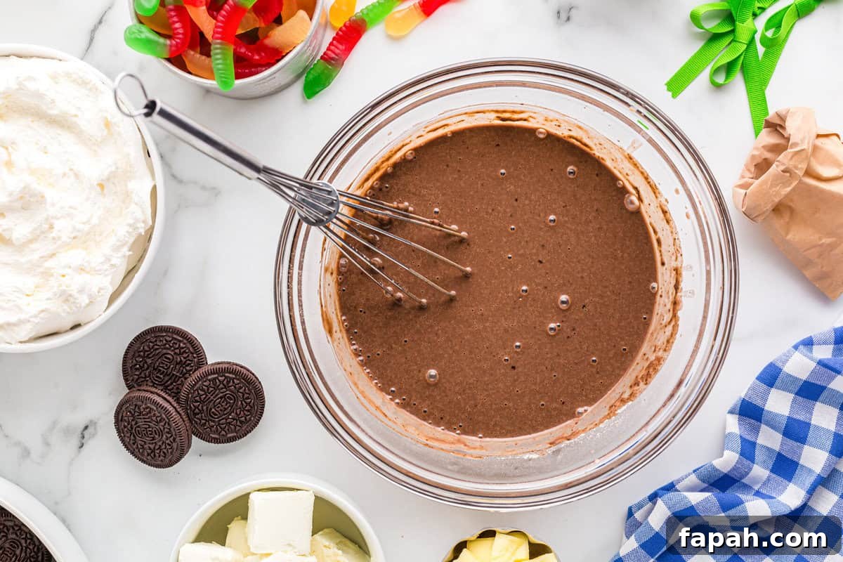 Chocolate pudding in a glass bowl with a whisk.