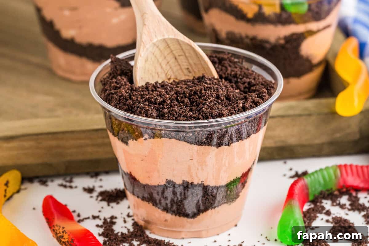 Layered dirt cake cup with a wooden spoon.