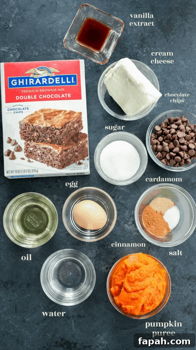Pumpkin Swirl Brownies with Spiced Cream Cheese Filling 3 Top-down view of ingredients for pumpkin cream cheese brownies, including brownie mix, cream cheese, chocolate chips, sugar, an egg, oil, water, pumpkin puree, cinnamon, cardamom, salt, and vanilla extract.