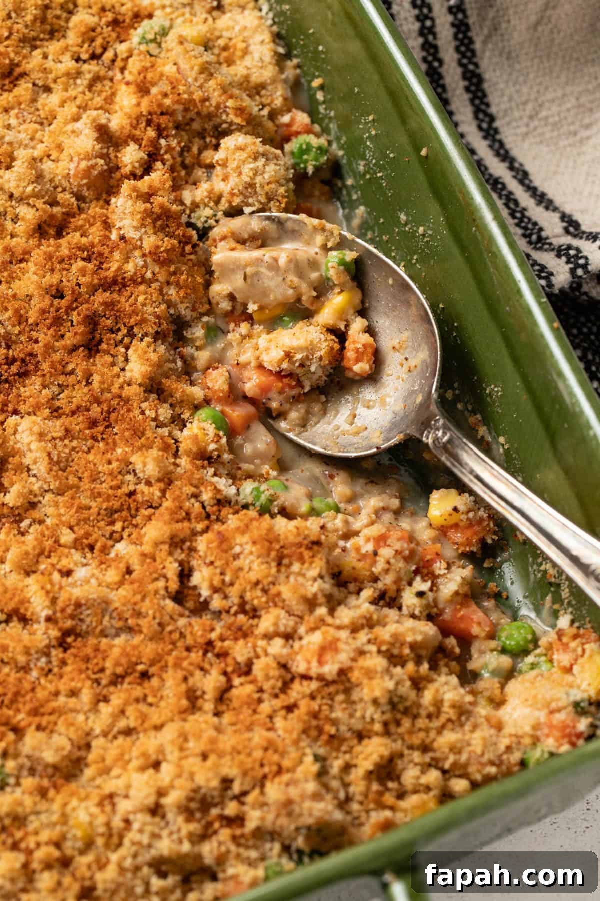 A spoon scooping up the chicken pot pie filling topped with crunchy panko.