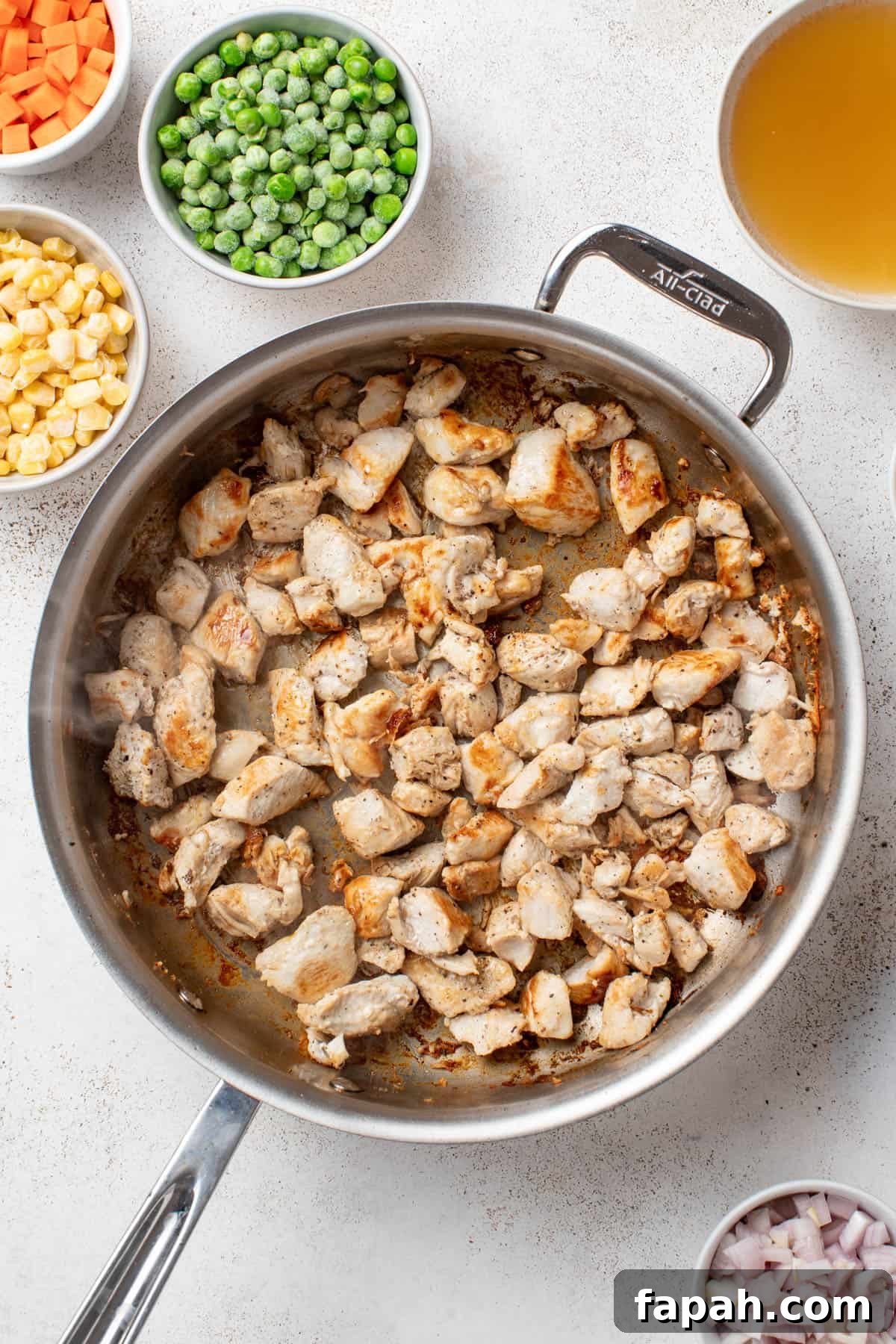 Browning chicken breast in a stainless steel pan.