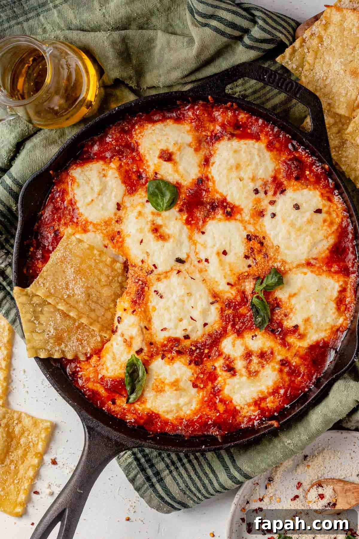 lasagna dip in a cast iron skillet with pasta chips and basil.