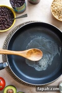 Overhead of step #1 with butter melted in a nonstick skillet with rice, black beans and other ingredients at edges of photo.