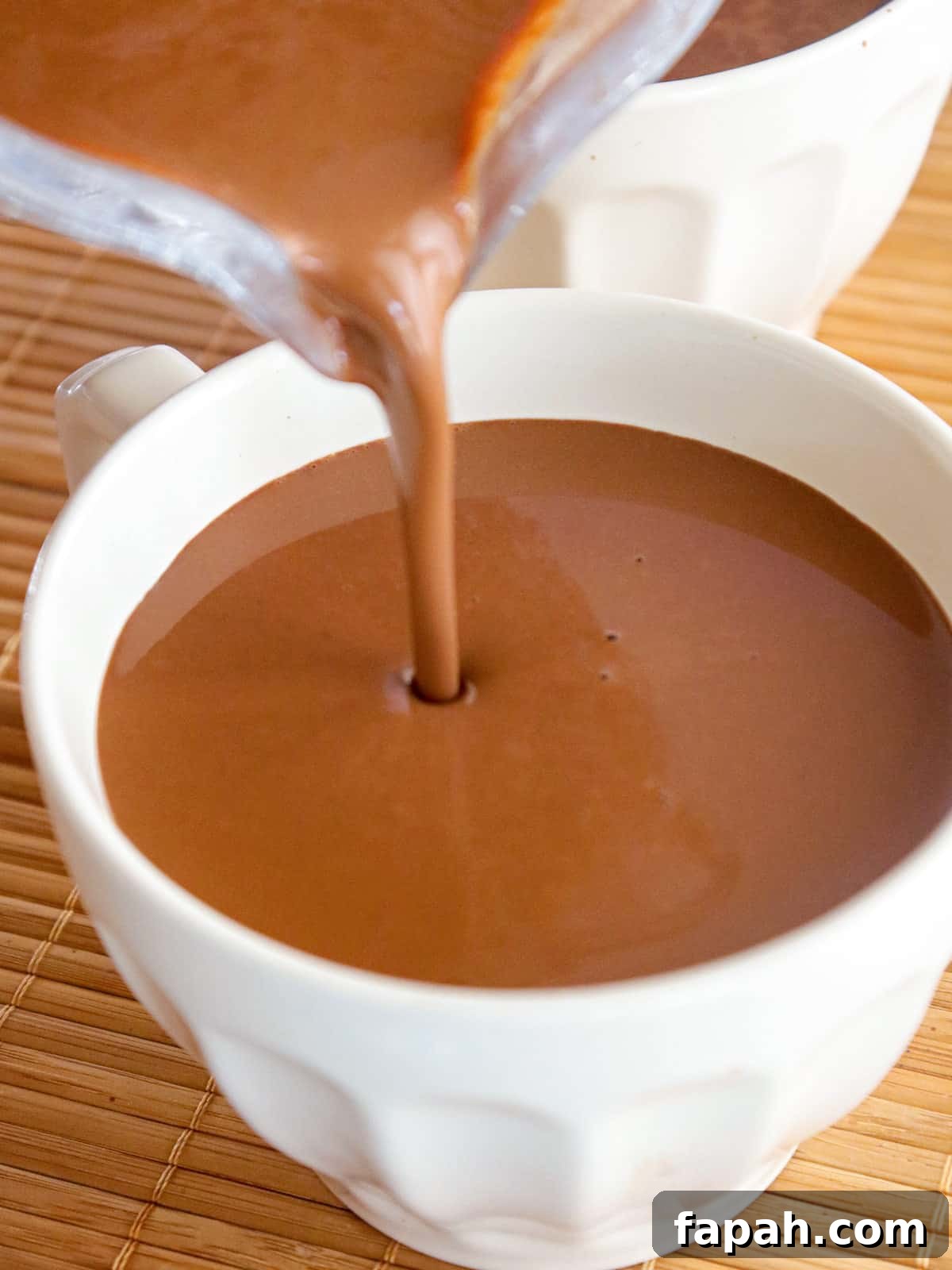 pouring hot tsokolate into a white cup.