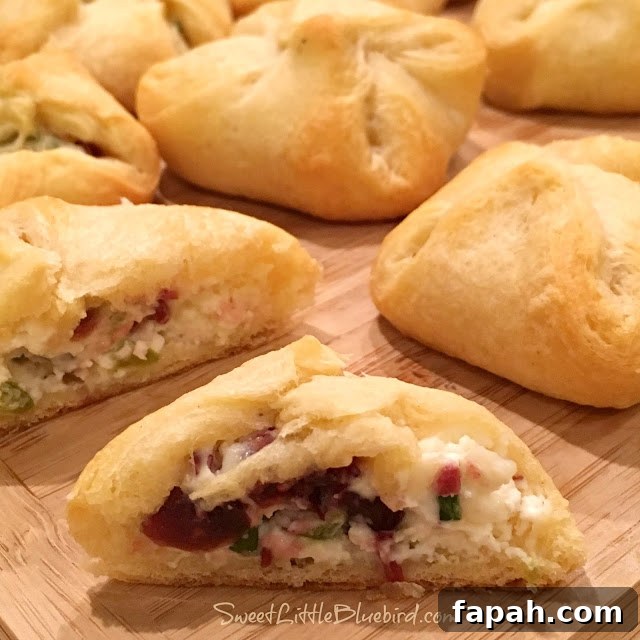 Cranberry and Cream Cheese Crescent Bites – 5-Ingredient Appetizer 5 This photo shows the crescent bites after baking, ready to eat on a cutting board. One is cut in half, showing the inside filling.