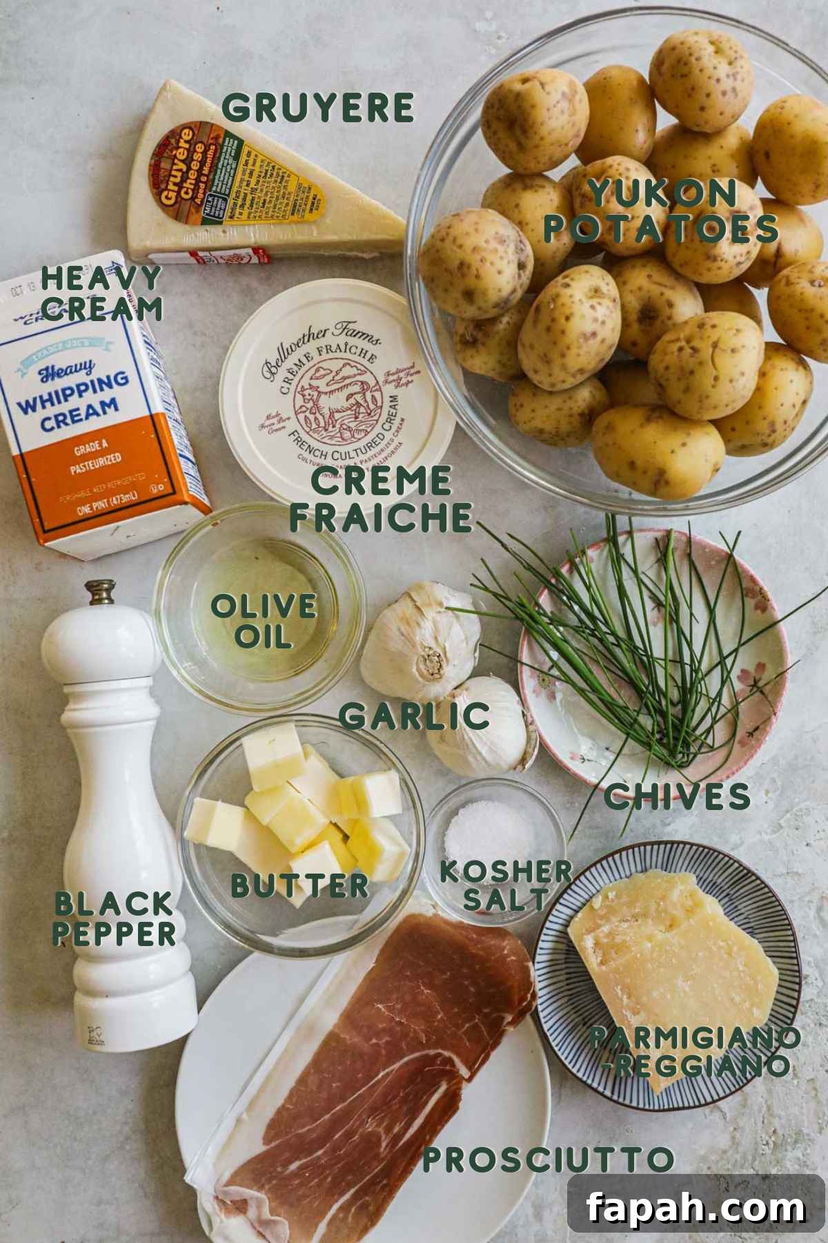 Ingredients to make twice-baked mashed potatoes, yukon potatoes, heavy cream, olive oil, garlic, chives, butter, parmigiano-reggiano, gruyere, prosciutto.
