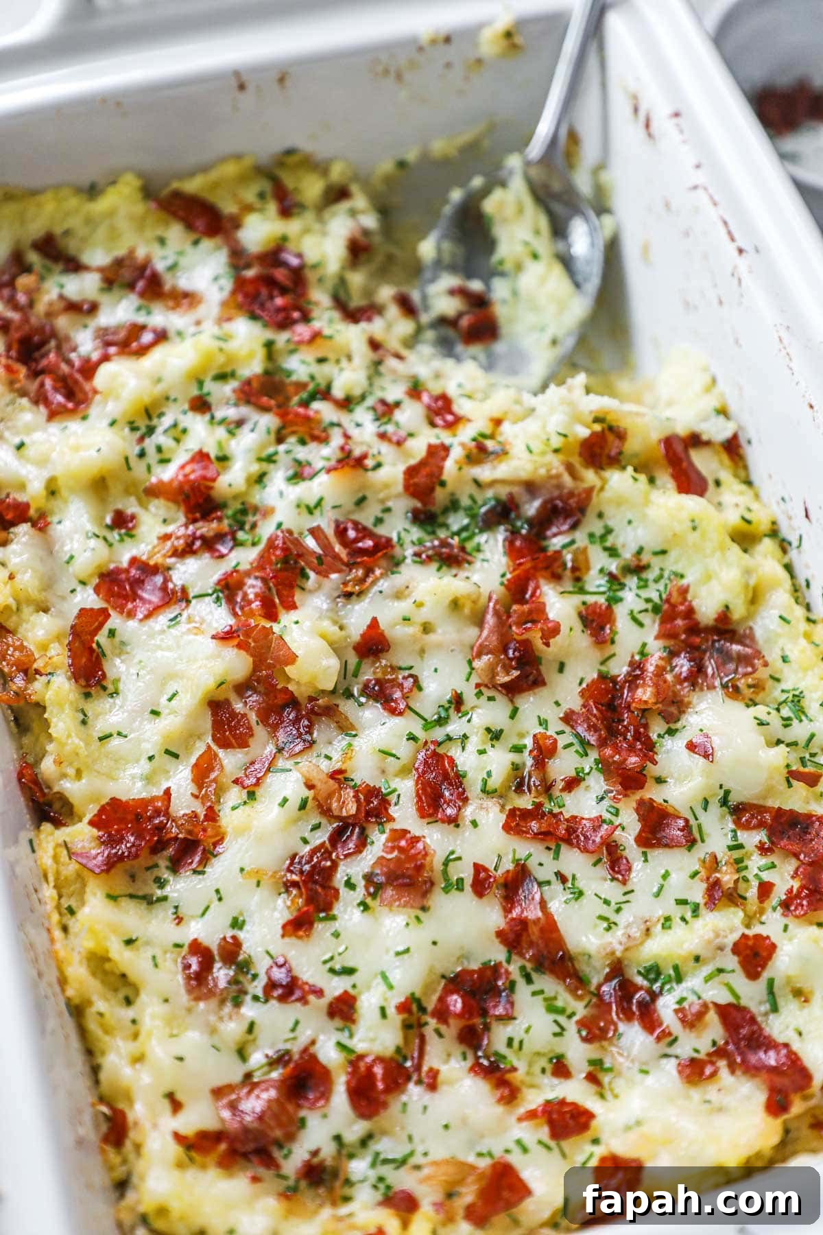 Twice-cooked mashed potatoes in a Le Creuset baking dish with gruyere, sour cream, chives, and crispy prosciutto.