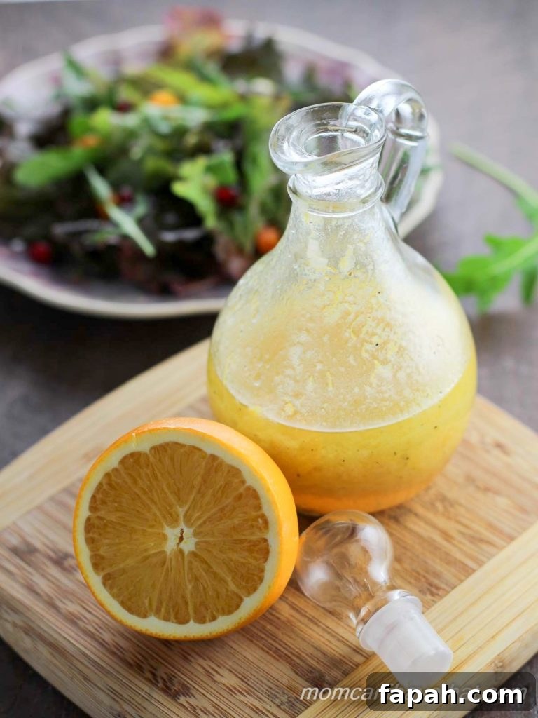 Orange Vinaigrette in a cruet with sliced orange and mixed green salad.