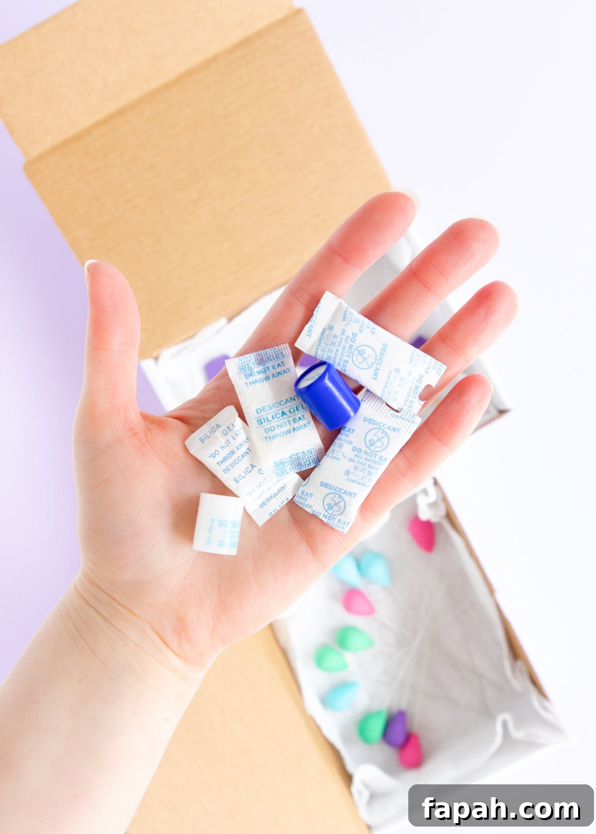 Storing Fondant Decorations: Tips to Keep Cakes Flawless 9 A hand holding silica gel packets to help store dry fondant decorations.