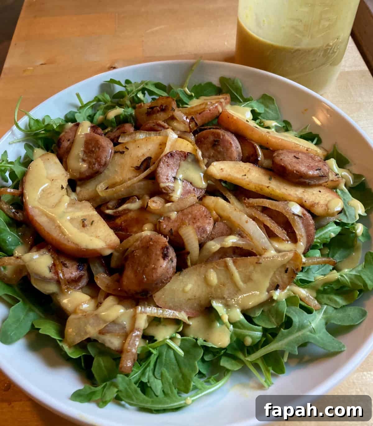 Arugula salad with sausage, apples and honey mustard dressing.