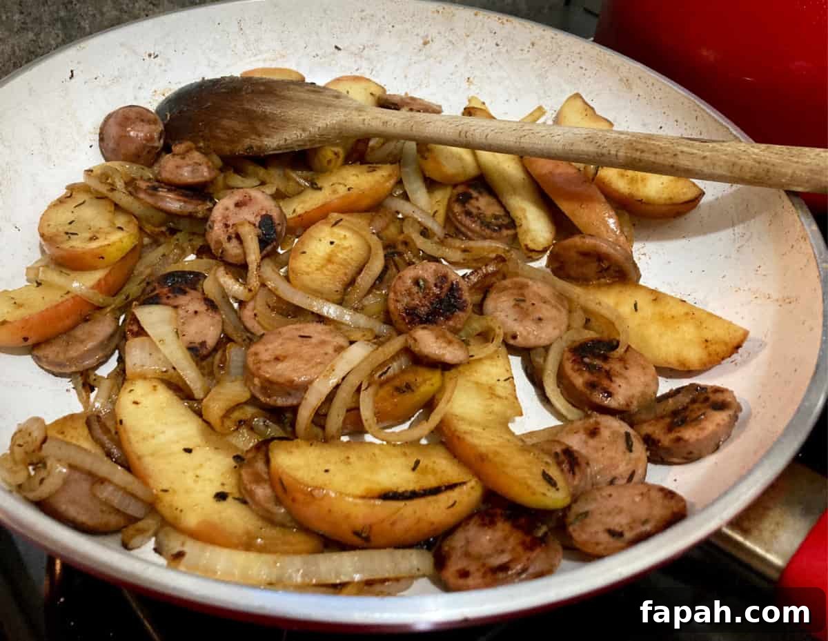 Cooking chicken sausage, apples and onions in skillet.
