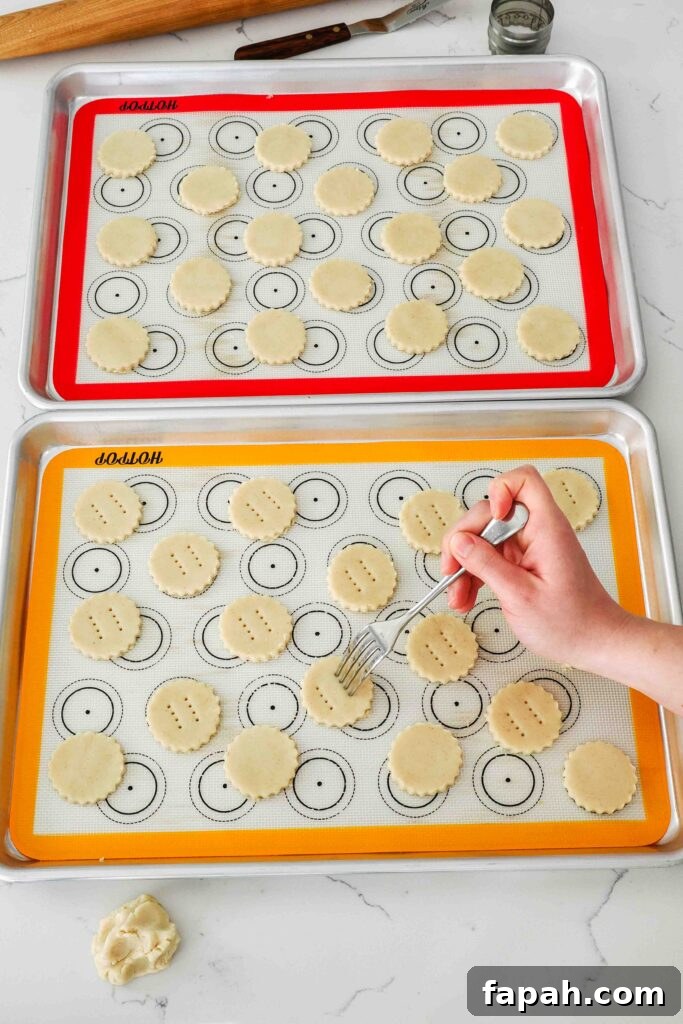 A fork docks shortbread cookies before baking.