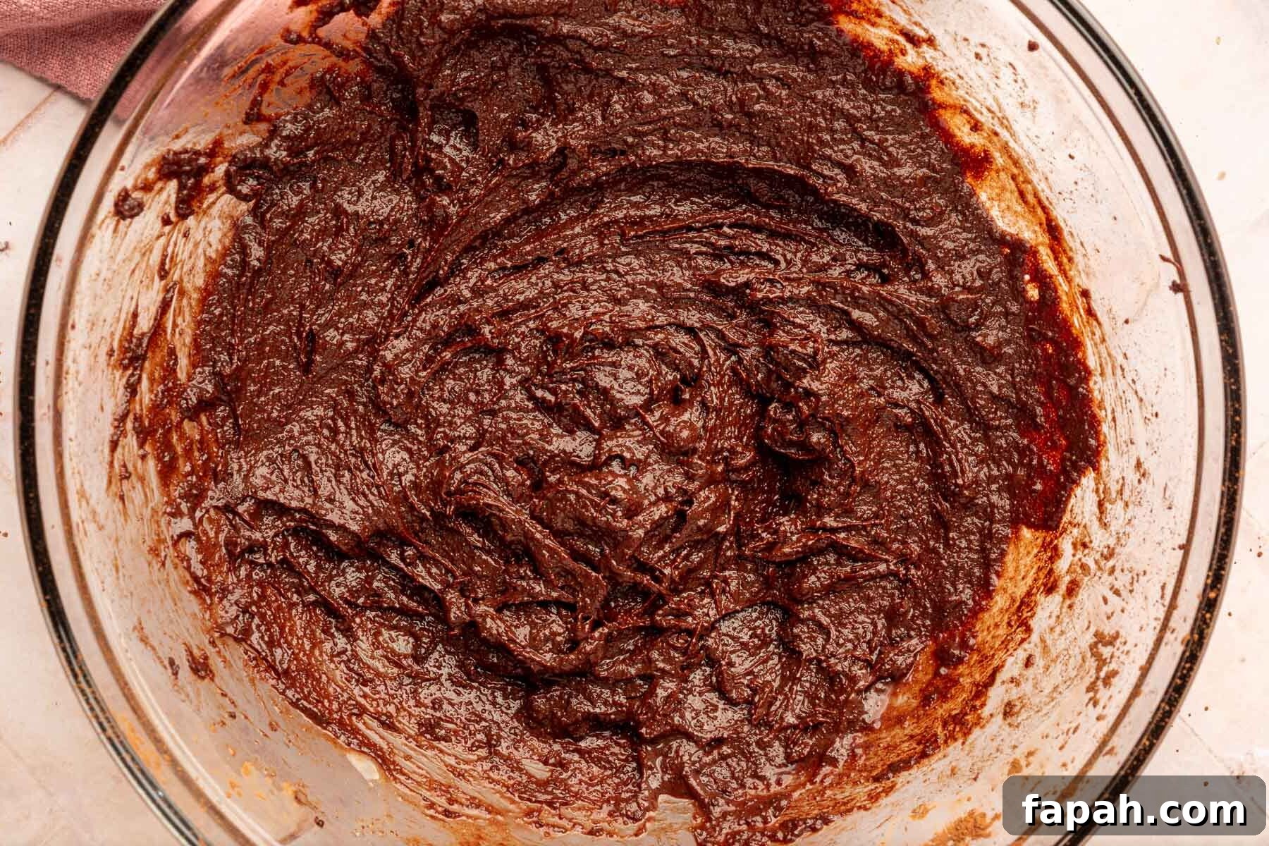A glass mixing bowl of gluten-free brownie batter in it.