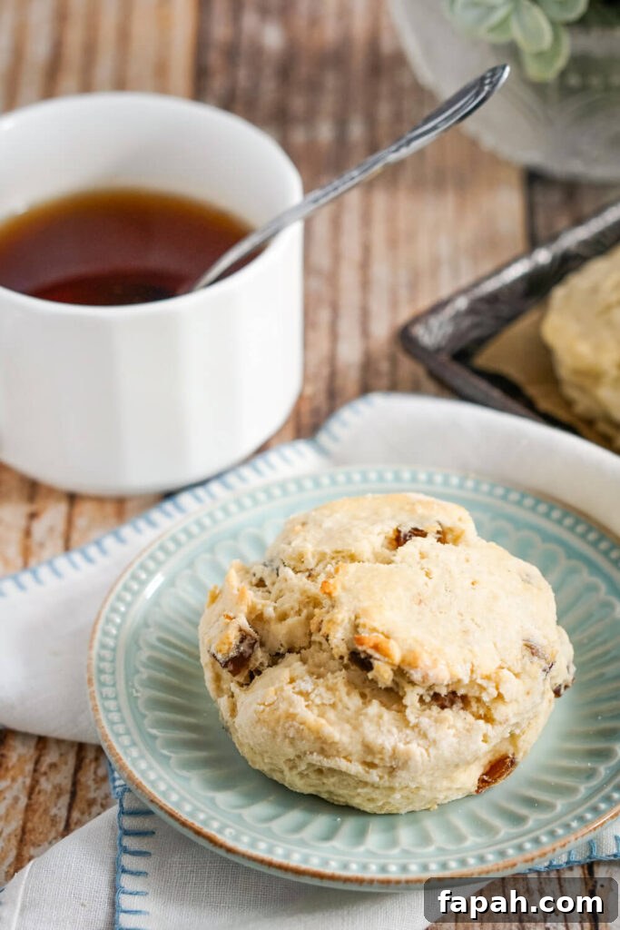 A Date Scone on a blue plate next to a cup of tea. 