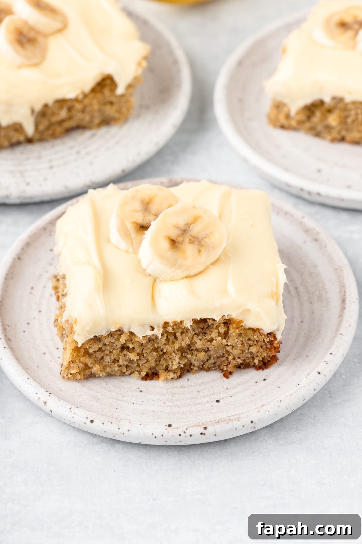 Banana cake made with fresh milled flour with cream cheese frosting sectioned off onto 3 small plates.