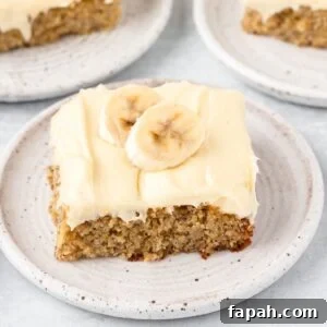 Banana nut coffee cake with cream cheese frosting on a white plate.