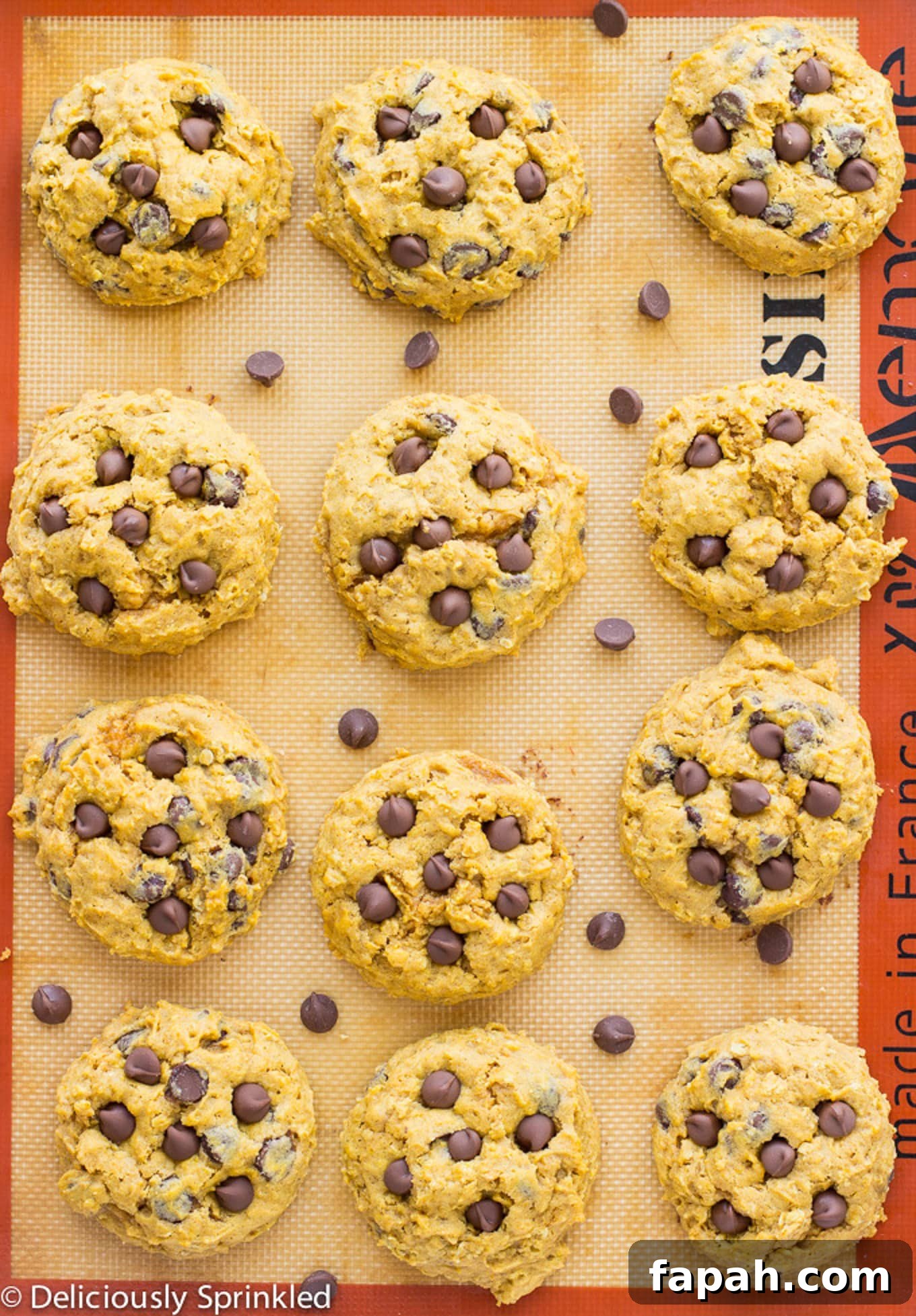 Chewy Pumpkin Oatmeal Cookies with Warm Spices 3 Soft pumpkin cookies on a silpat on a baking tray after cookie with chocolate chips spilled on the tray.