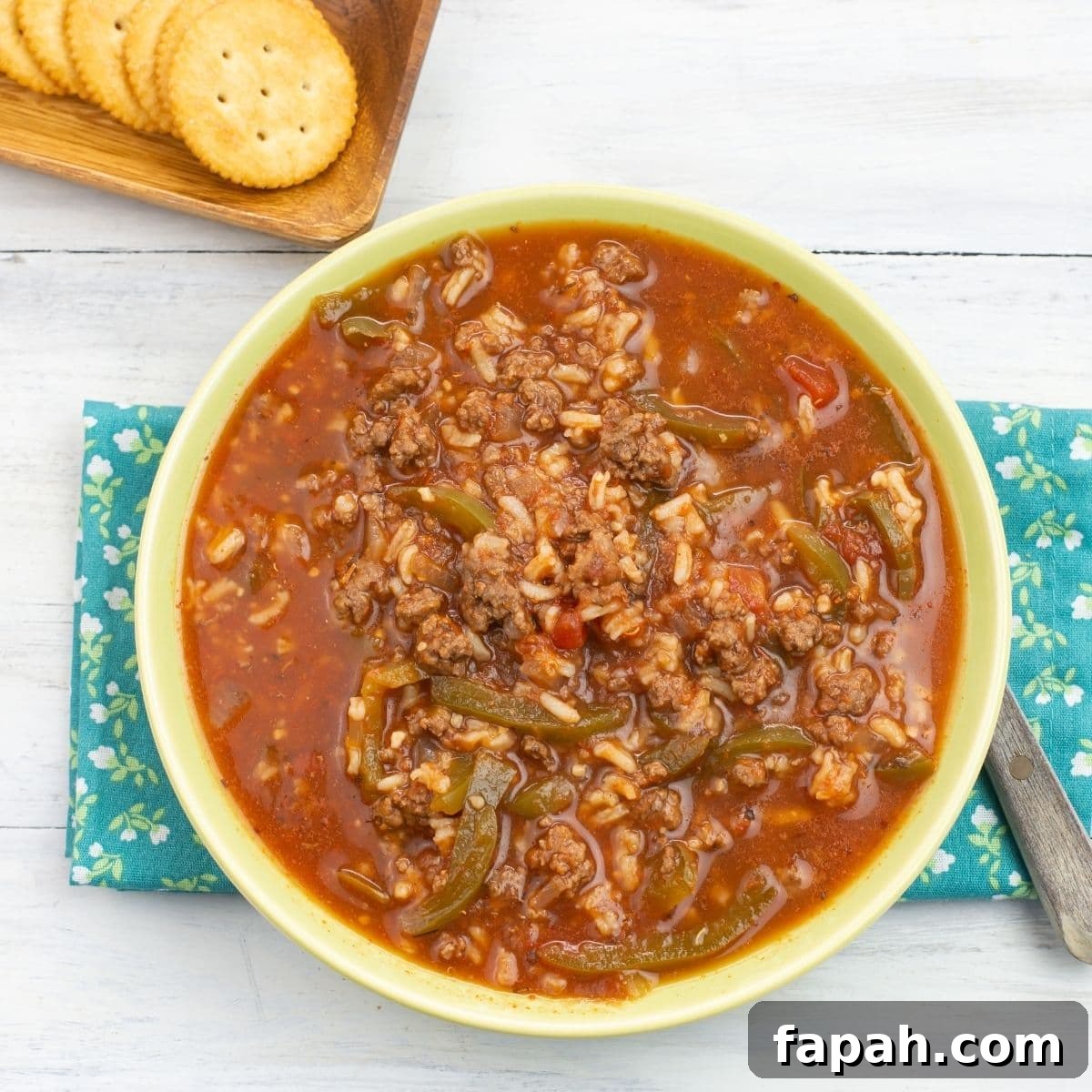 Instant Pot Stuffed Pepper Soup served in a green glass bowl with crackers on the side.