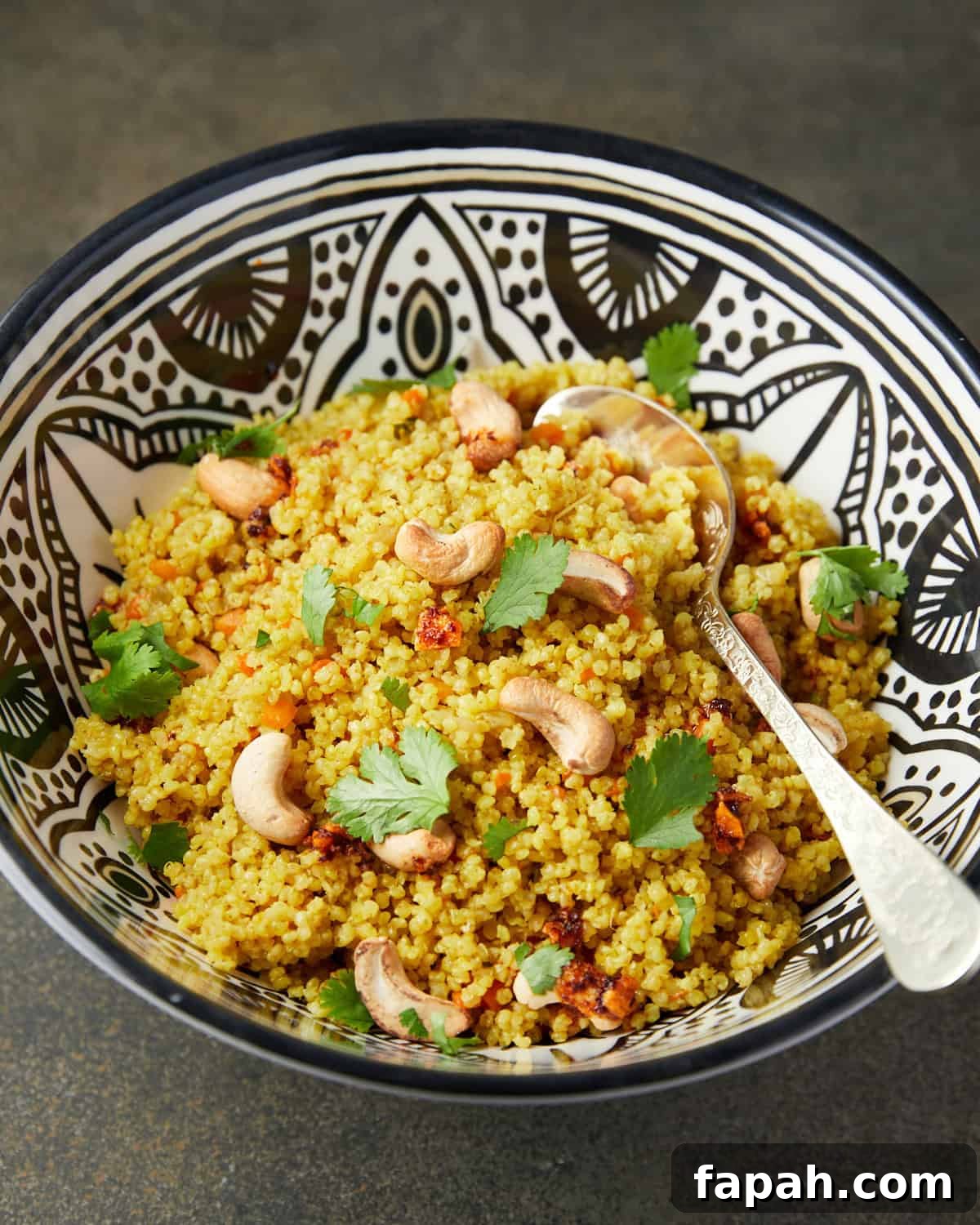 Photo of millet pilaf in a black and white patterned bowl on a green background.