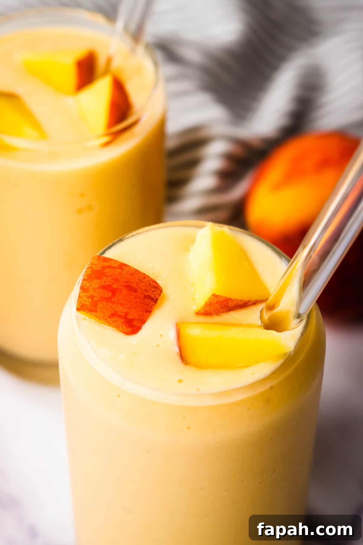 Creamy Peach Banana Smoothie Recipe for Refreshing Mornings 2 A glass of banana peach smoothie topped with fresh peaches.