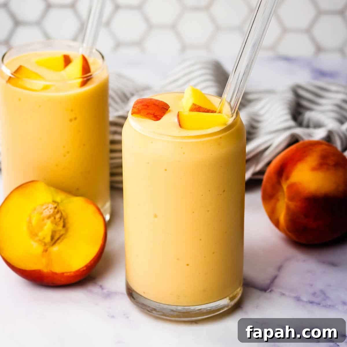 Creamy Peach Banana Smoothie Recipe for Refreshing Mornings 3 Two banana peach smoothies garnished with chopped peaches and glass straws.