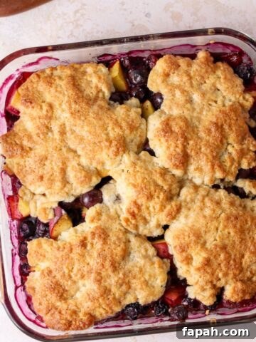 Peach and blueberry cobbler in a square glass baking dish.