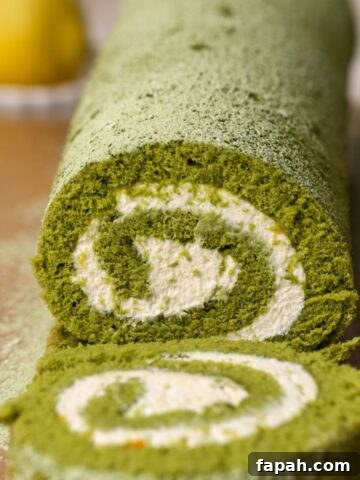 A matcha cake roll with mascarpone filling being sliced.