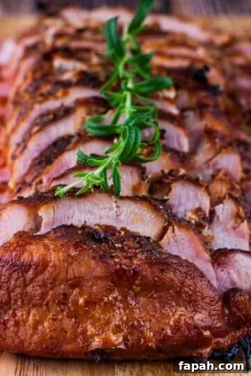 Smoked pork loin roast cut in slices on a wooden cutting board.