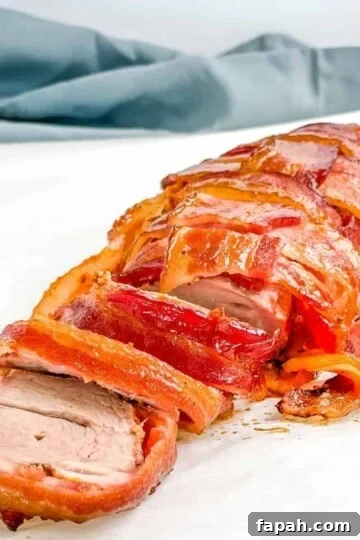 Sliced smoked bacon wrapped pork tenderloin on a white table.