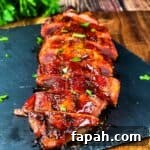 Smoked pork tenderloin sliced on a serving platter, garnished with fresh herbs.