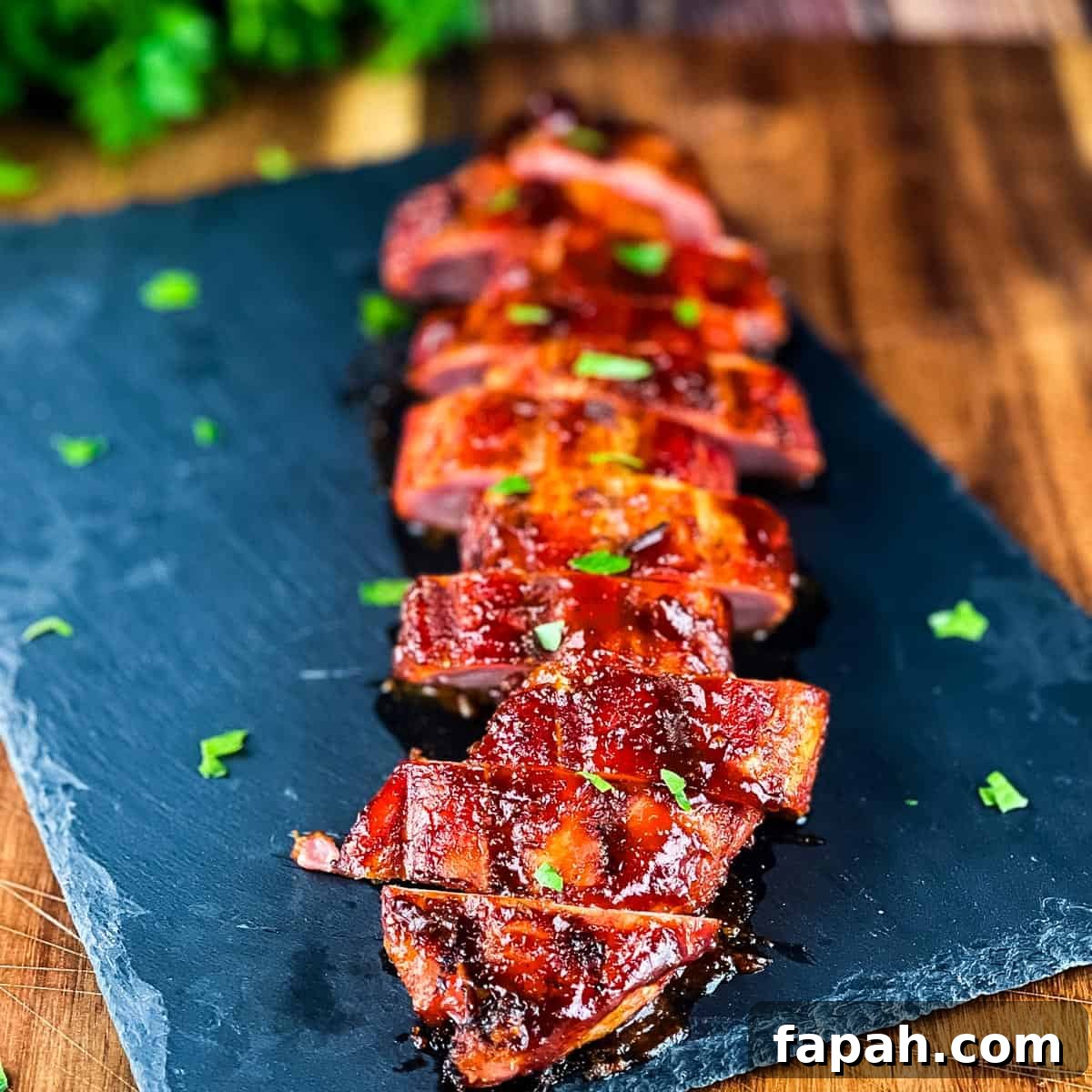 Sliced smoked pork tenderloin on a serving platter, garnished with fresh herbs.