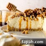 Goat Cheese Cheesecake with Roasted Honey Walnut Topping 15 A sliced goat cheese cheesecake sitting on a plate with a jar of honey and a honey stick in the background and a plate of goat cheese in the foreground.