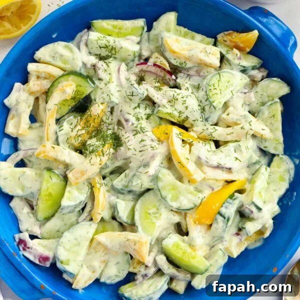 A blue salad bowl filled with cucumber salad with yoghurt dressing.