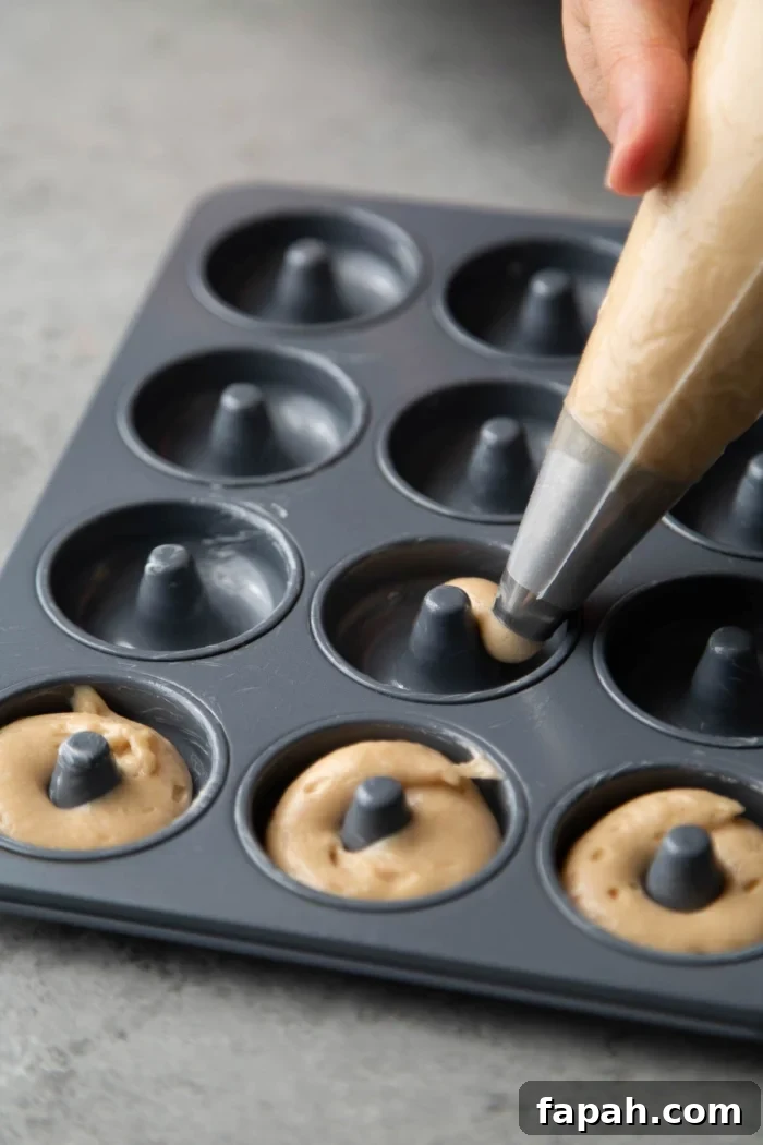 Spooky Halloween Donuts: Creative Recipes and Decorating Ideas 7 use piping bag to fill prepared donut pans with batter.