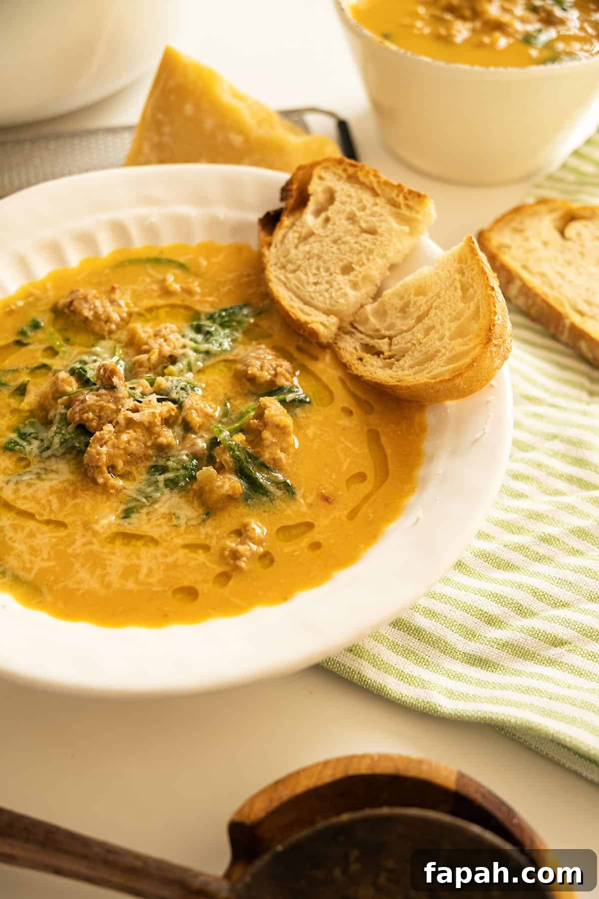 Creamy Butternut Squash and Sausage Soup Recipe 2 Butternut squash soup with sausage in a bowl and side of crusty Italian bread.