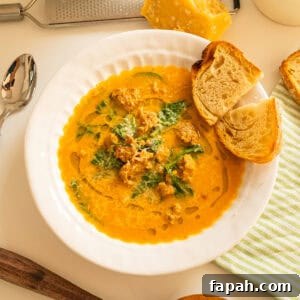 Creamy Butternut Squash and Sausage Soup Recipe 13 Butternut squash soup with sausage in a bowl and side of crusty Italian bread.