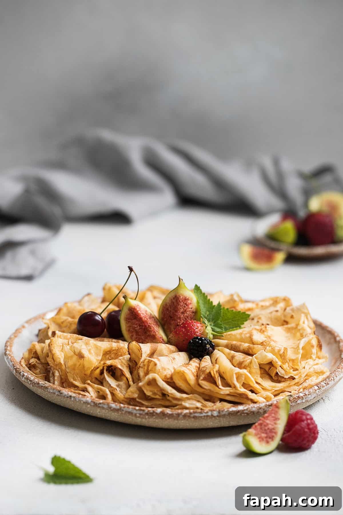 Folded French crepes topped with fresh fruit on a serving plate.