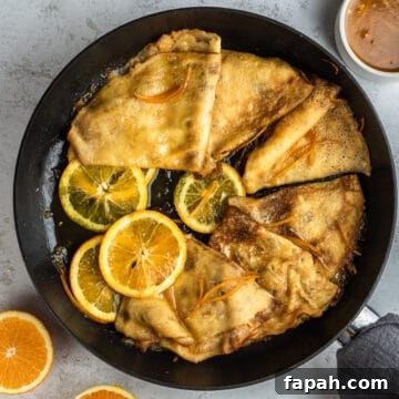 Crepes Suzette with orange slices in a skillet.