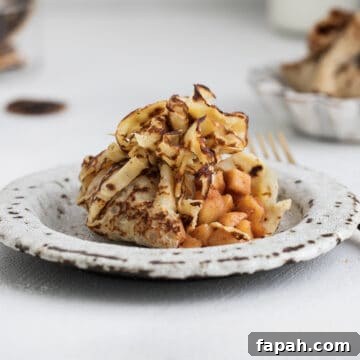 French crepe filled with caramelized apples and cinnamon, served on a dessert table.