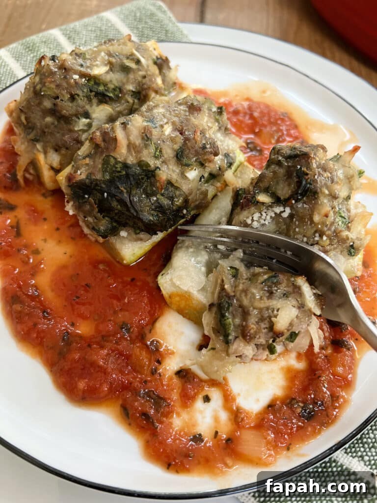 Fork cutting into one piece of stuffed cucuzza squash over tomato sauce on a white plate.