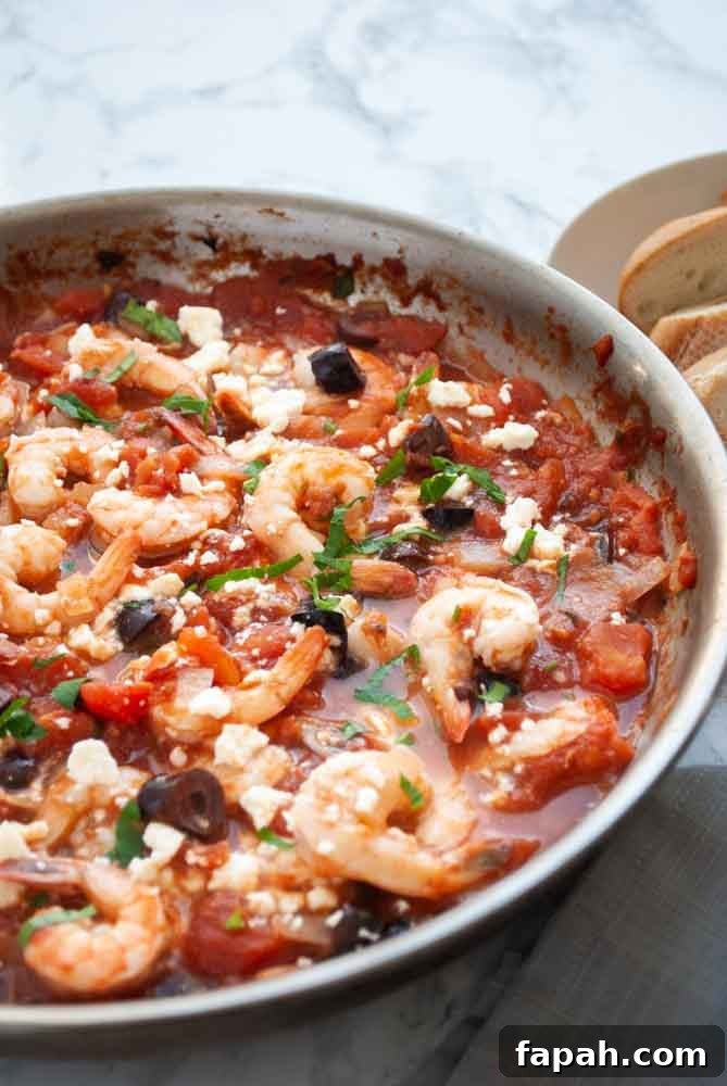 A pan filled with greek style shrimp cooked in tomatoes with feta cheese.