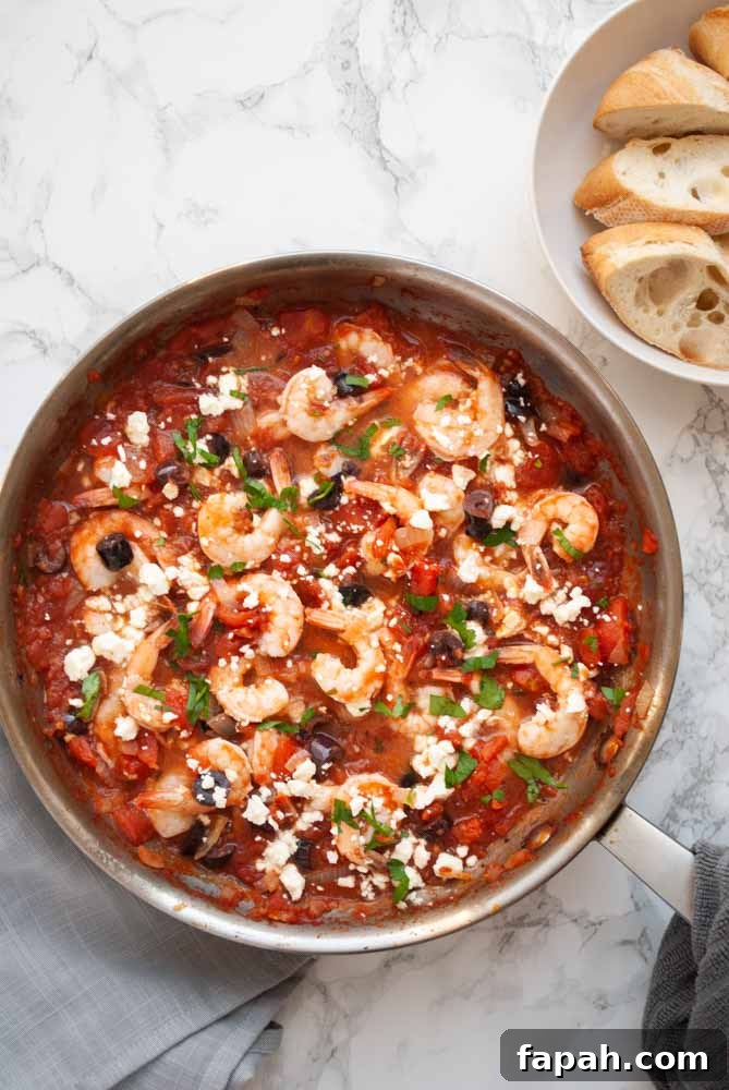 A sauce pan filled with shrimp cooked in a Greek style tomato sauce and sprinkled with feta cheese.