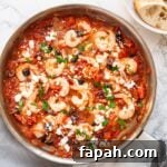 A top down view of Greek shrimp with tomatoes and feta cheese in a skillet.