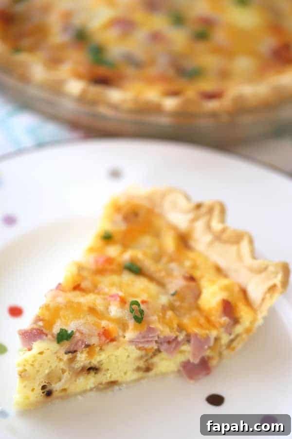 A plate with a slice of egg and ham quiche.
